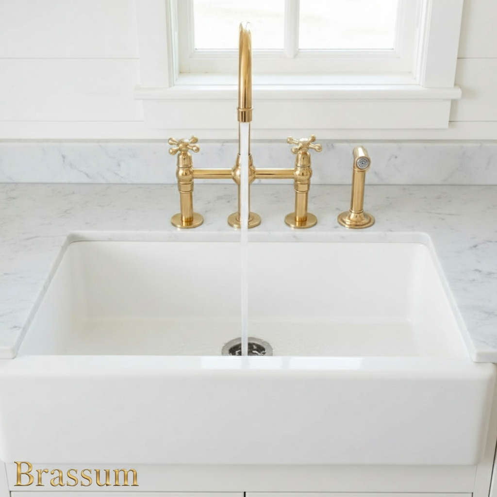 White kitchen sink with gold faucet and handles on a marble countertop.