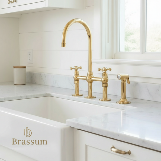 Unlacquered solid brass bridge faucet with side sprayer mounted on a white farmhouse sink and marble countertop, handmade by Brassum artisans in Marrakech.